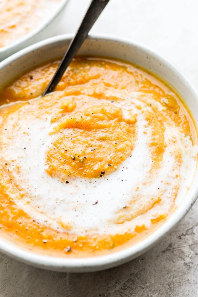 Creamy acorn squash soup in a white bowl with a spoon.