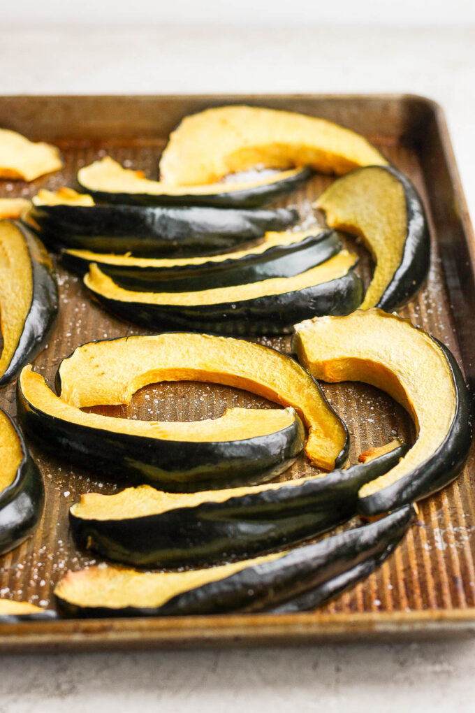 Sliced acorn squash on a baking sheet pan.