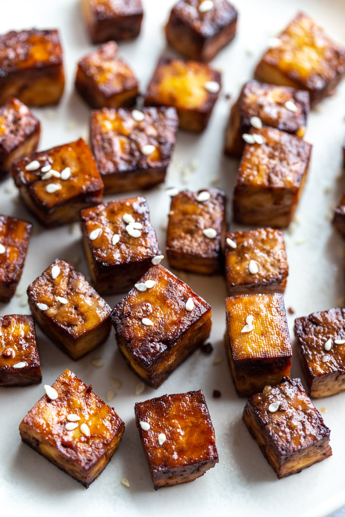 crispy air fryer tofu on a plate and topped with sesame seeds