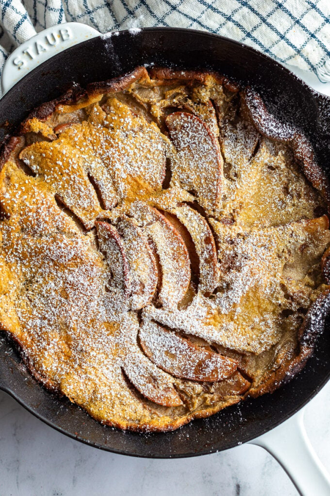 shot of an apple dutch baby in a cast iron skillet. Dusted with powdered sugar