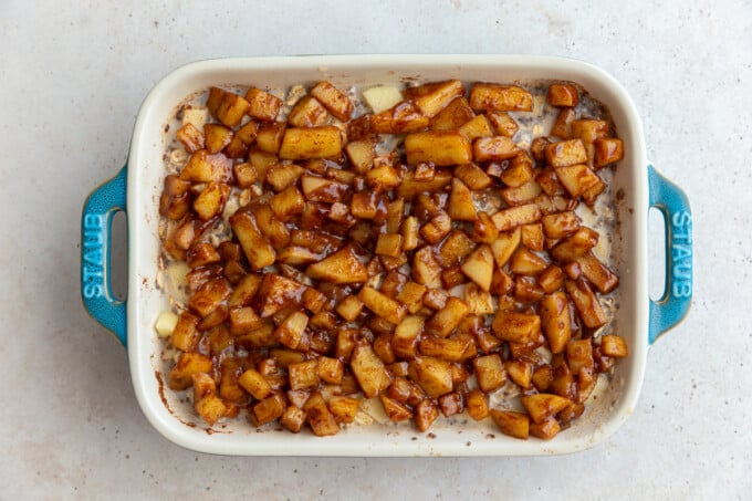 baked oatmeal topped with cinnamon apple chunks in a small teal baking dish