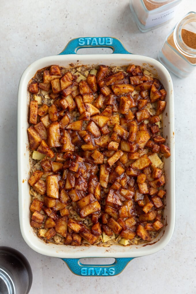 baked oatmeal topped with cinnamon apple chunks in a small teal baking dish