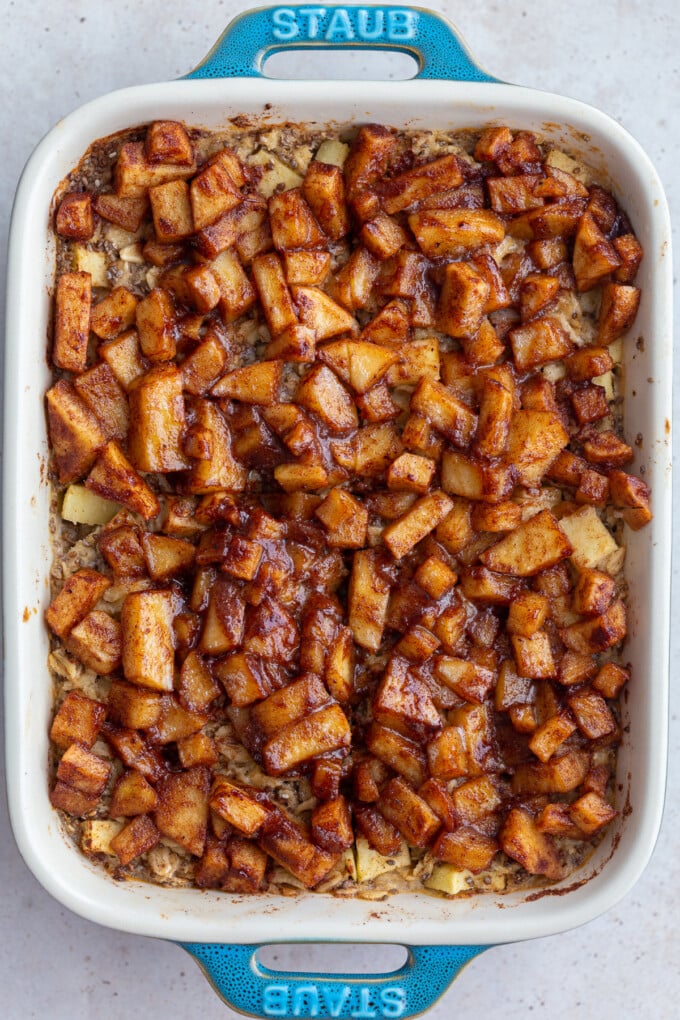 baked oatmeal topped with cinnamon apple chunks in a small teal baking dish