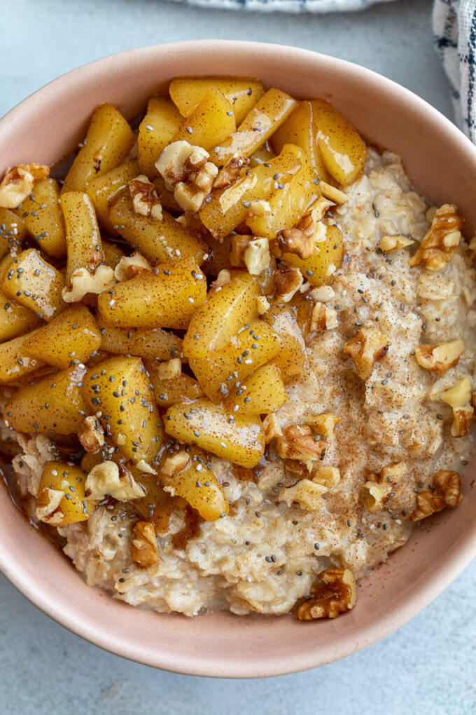 Oatmeal topped with cinnamon apple pieces and chopped walnuts.