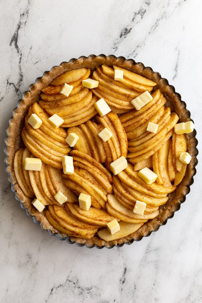 unbaked apple tart that has small cubes of butter all around