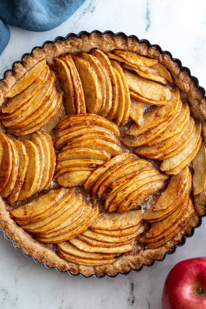 Baked apple tart on a marble board. The tart has apple arranged in groups that are going in different directions