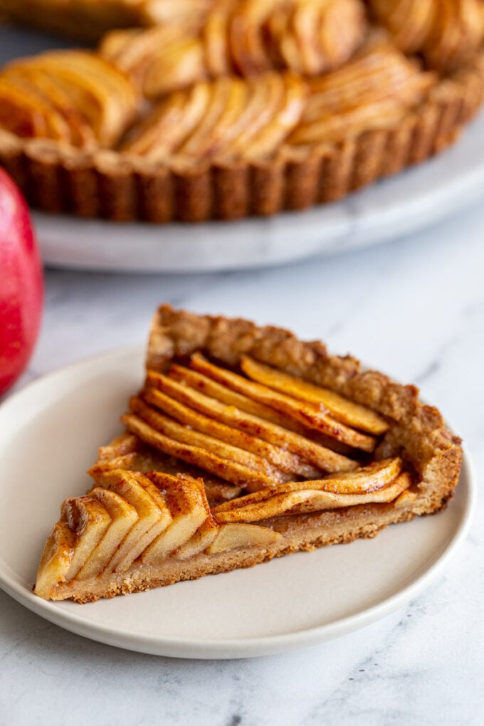 single slice of apple tart with a red apple in the background