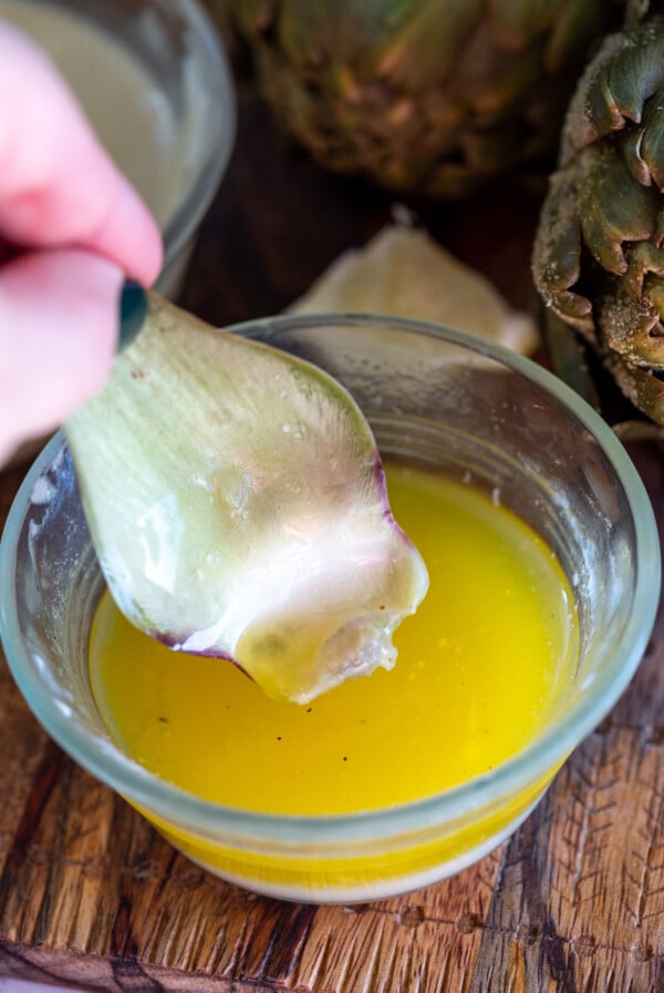 piece of artichoke being dipping in lemon butter