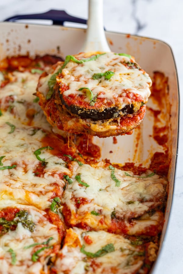 Using a spatula to serve a slice of baked eggplant parmesan.