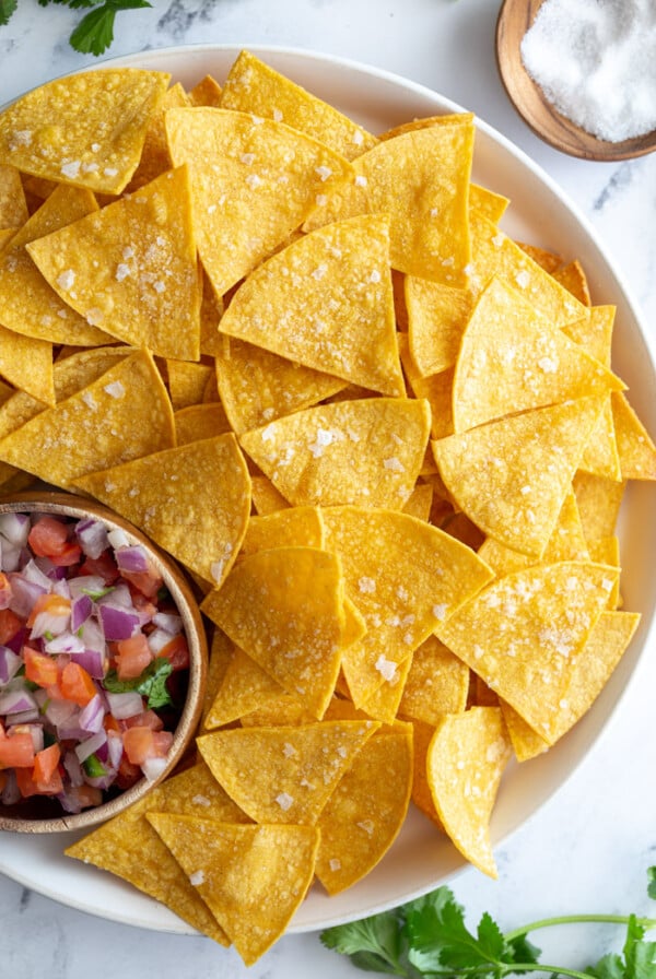 large plate of homemade tortilla chips with a bowl of pico de gallo on the plate