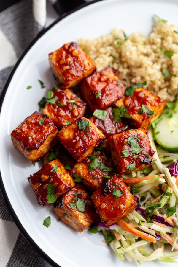 large white dish with quinoa and coleslaw in the corner with the highlight being large cubes of bbq tofu