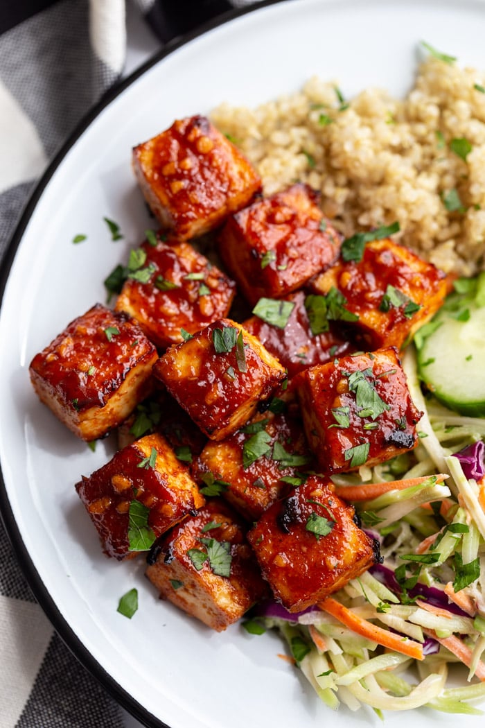 large white dish with quinoa and coleslaw in the corner with the highlight being large cubes of bbq tofu