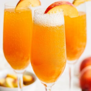 Peach bellini drinks garnished with sliced peach.