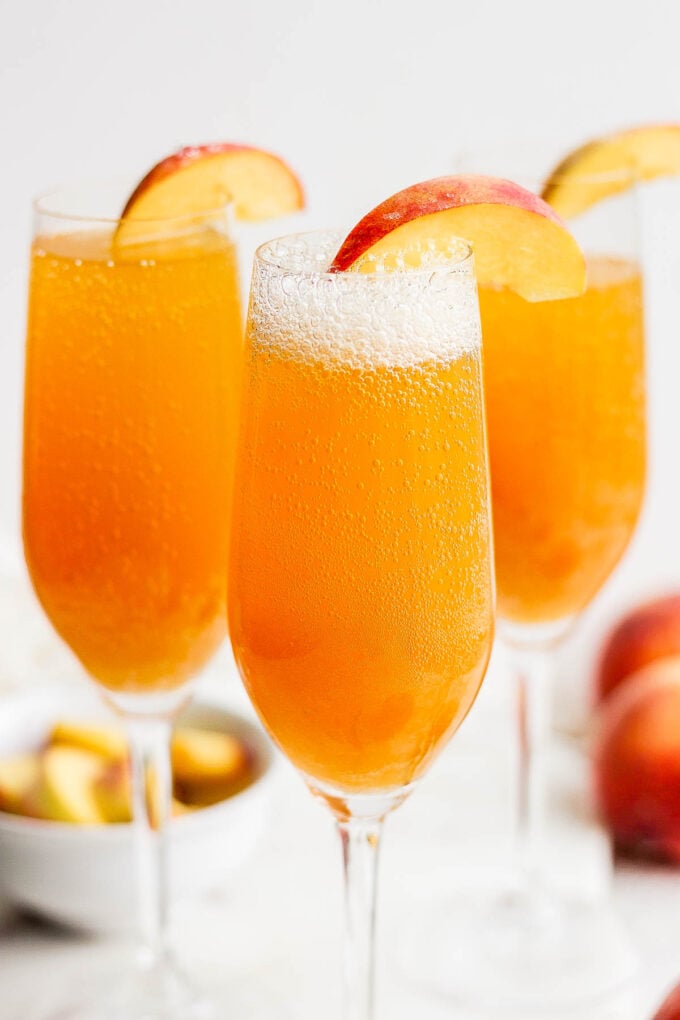 Peach bellini drinks garnished with sliced peach.