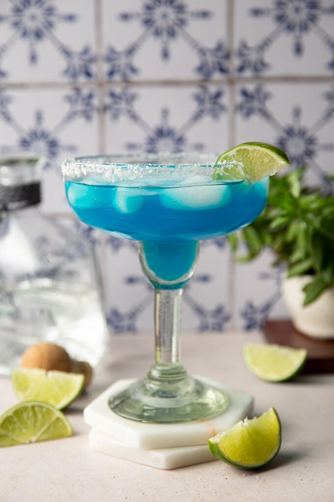 Blue margarita served with lime slices.