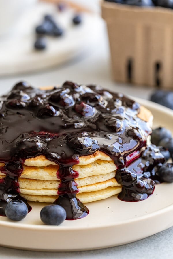 Blueberry syrup served over a stack of pancakes.