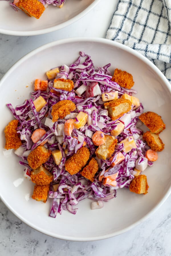 2 wide bowls of cabbage and carrot salad that are topped with diced buffalo wings