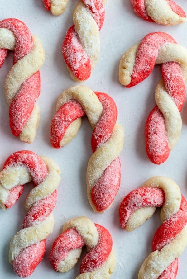 red and white sugar cookies that are twisted to look like candy canes. All laying on parchment paper