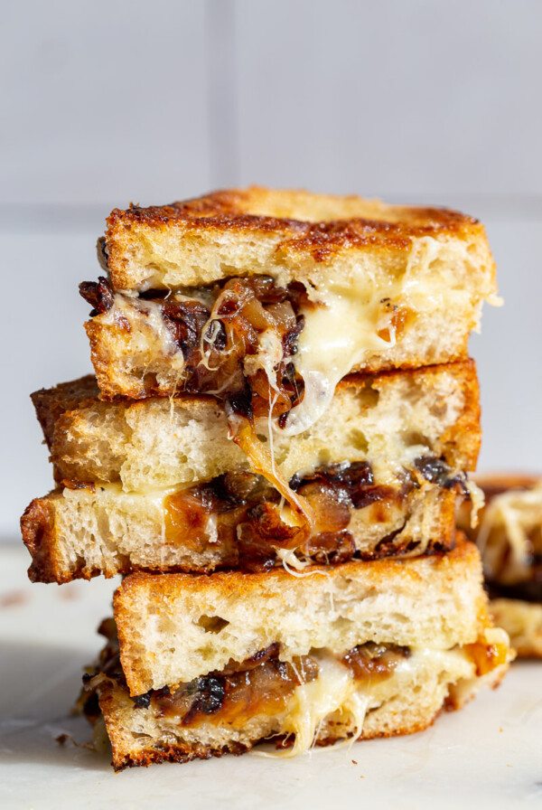 Caramelized Onion grilled cheese stacked on top of itself with cheese and onion oozing out