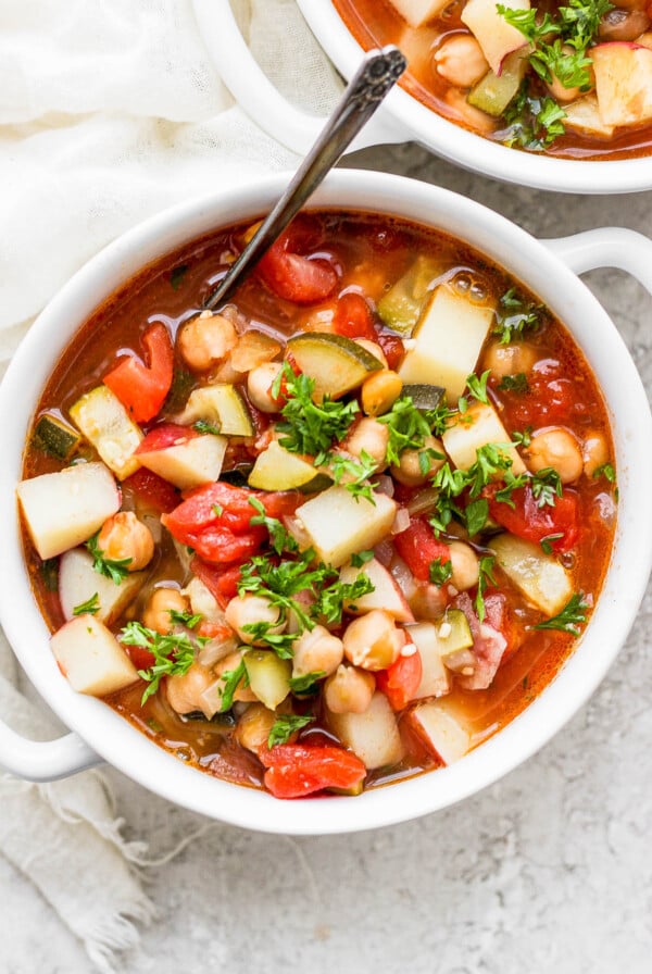 Moroccan chickpea soup served in a white bowl with a spoon.