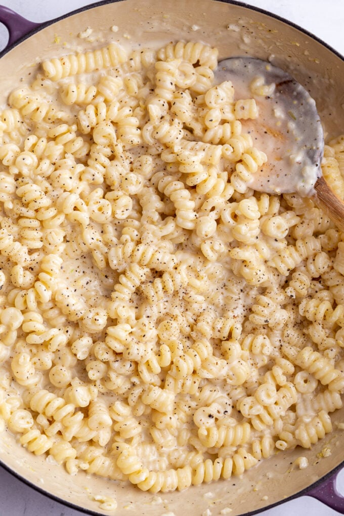 Stirring creamy noodles in a large pan.