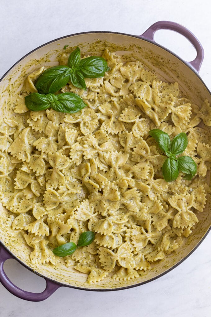 Pasta in a large skillet garnished with fresh basil.