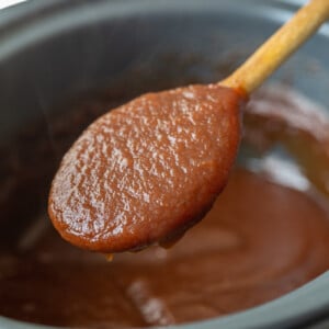 apple butter in a slow cooker with a spoonful being held up to the camera