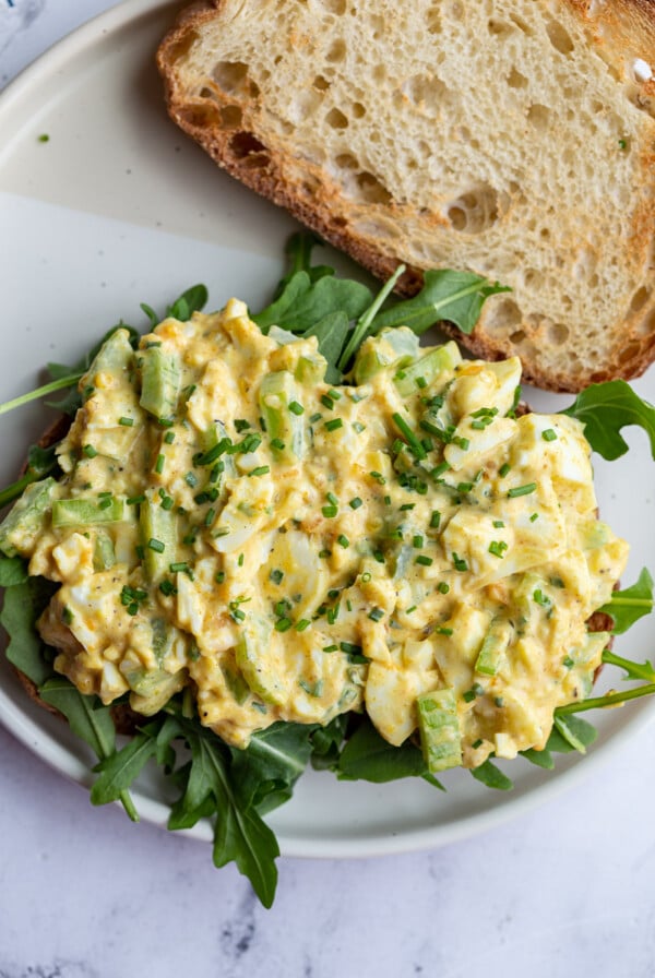 curried egg salad on toast with arugula on a plate