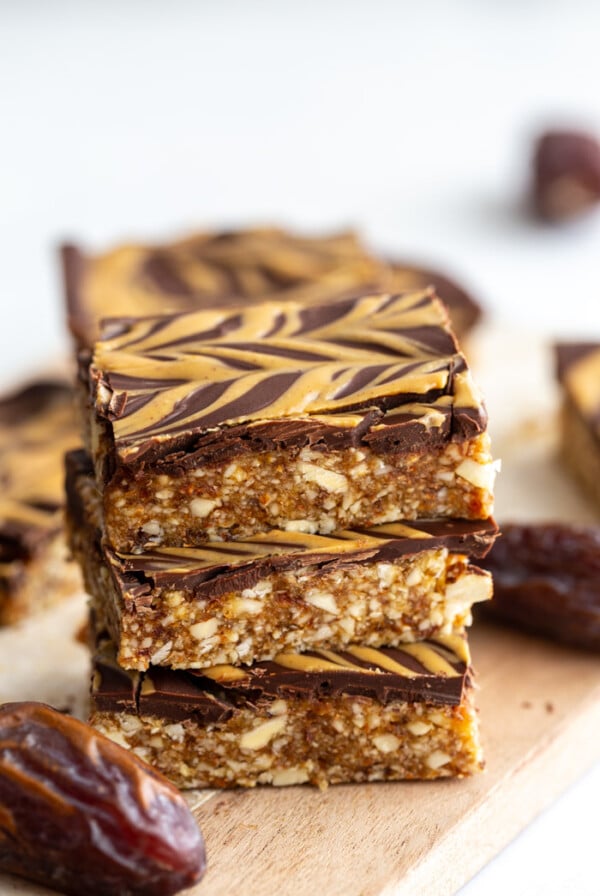 date and nut bars topped with chocolate and peanut butter drizzle. 3 bars stacked on top of each other