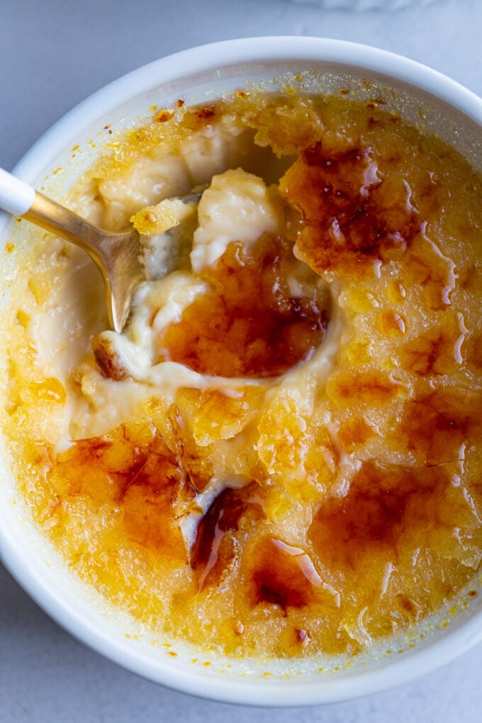 A spoon in a small bowl with Crème Brûlée.