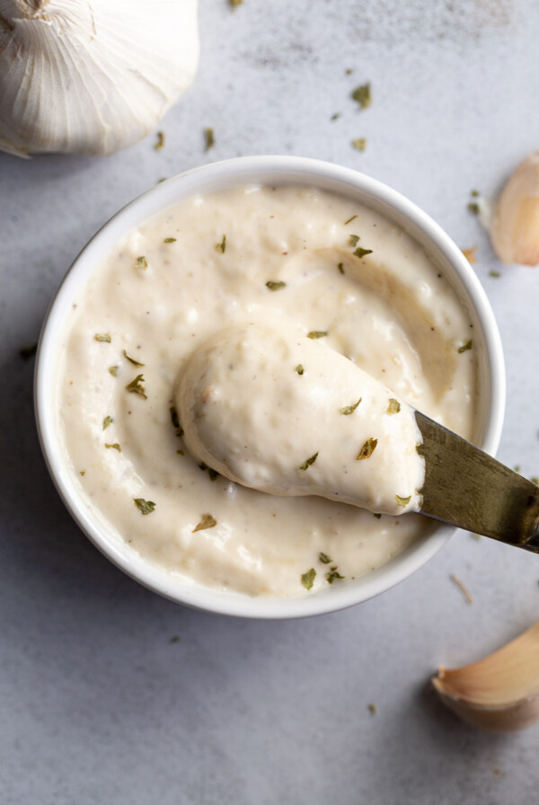 Spooning out Roasted Garlic Aioli from a small bowl.