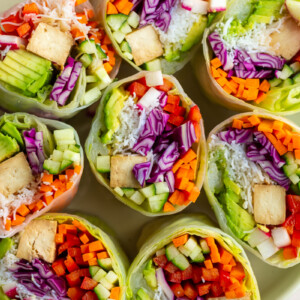 giant summer rolls stuffed with cabbage, radish, avocado, bell pepper, cucumber, tofu, and carrot. they're cut in half so you can see everything inside