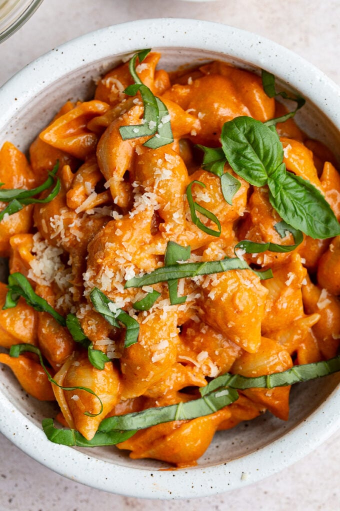 Pasta topped with fresh basil in a small white bowl.