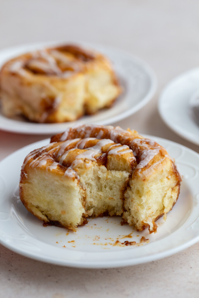 cinnamon roll on a white plate with a bite taken out of it