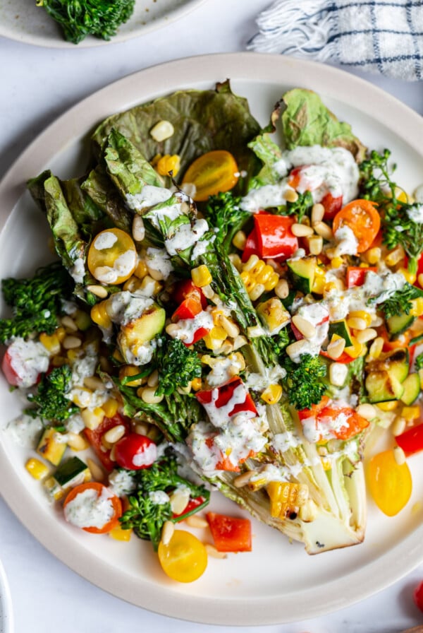 grilled romaine lettuce topped with mixed veggies and a white salad dressing