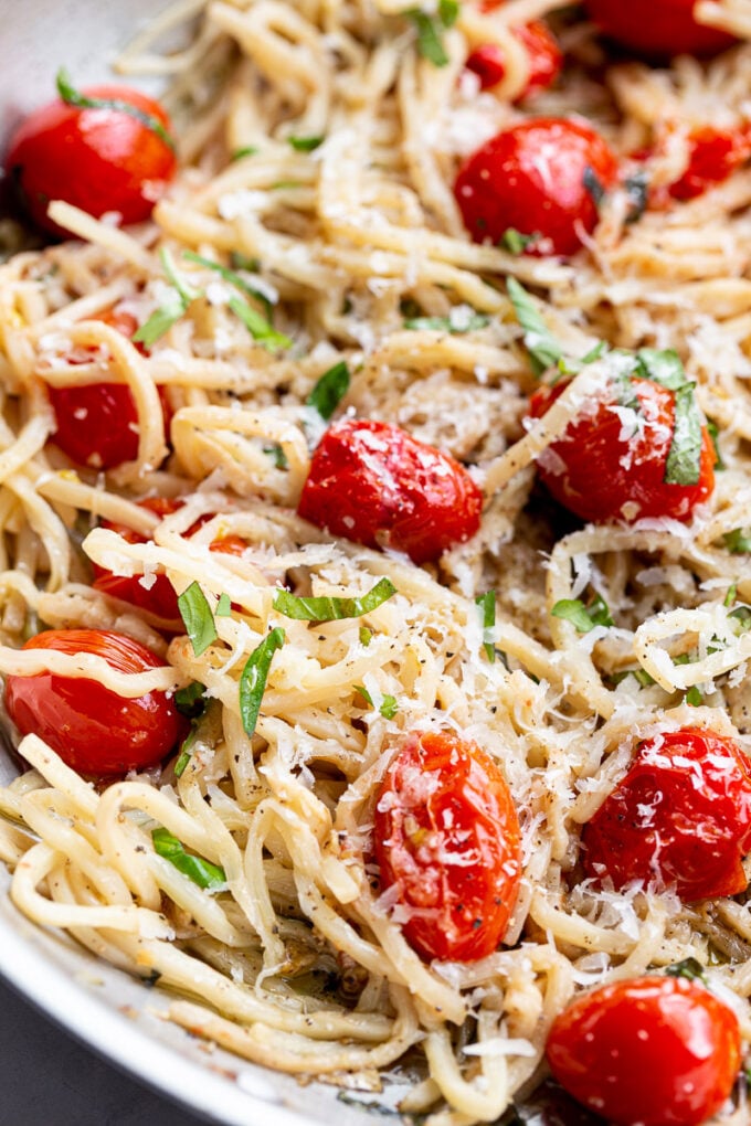 Noodles topped with fresh basil, parmesan cheese and tomatoes.