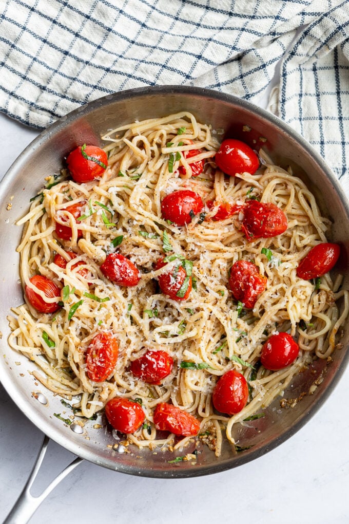 Pasta noodles and cherry tomatoes cooked in a large skillet.