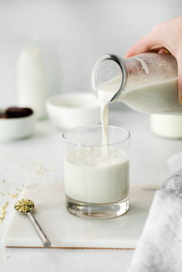 pouring homemade hemp milk into a glass