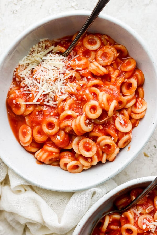 Pasta serve in a white bowl and topped with parmesan cheese.