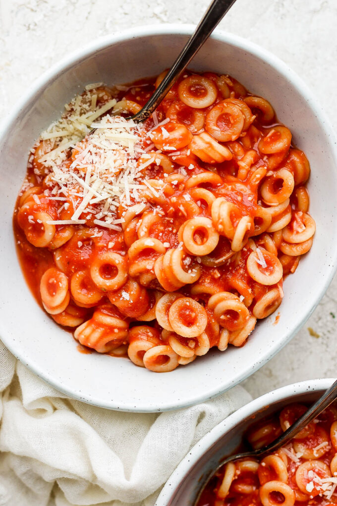 Pasta serve in a white bowl and topped with parmesan cheese.