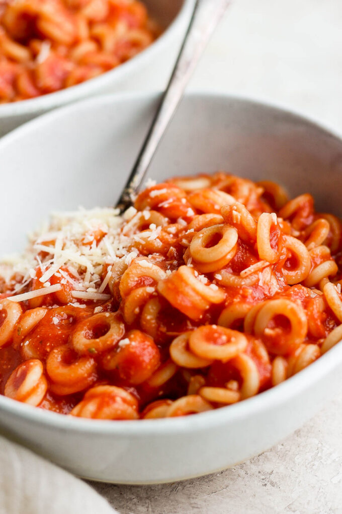 Homemade spaghettios pasta in a white bowl with a spoon.