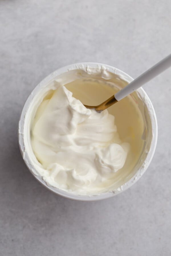 top down shot of a tub of sour cream with a spoon swirled in it