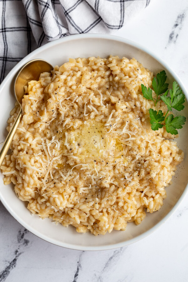 Risotto in a white bowl garnished with fresh parsley.