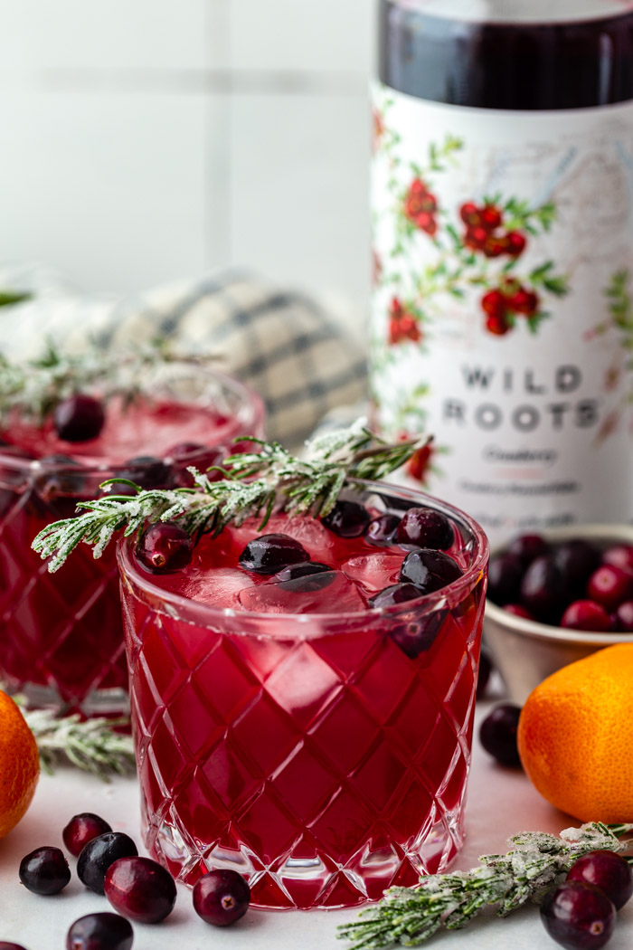 cranberry cocktail with rosemary on top and a bottle of cranberry vodka in the background