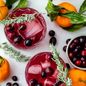 top down shot of a cranberry whiskey cocktail with fresh cranberries in it and sugared rosemary sitting on the rim