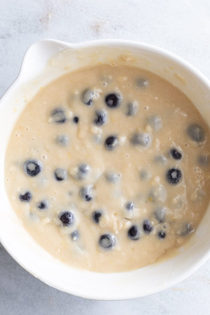 Mixing blueberries with batter in a large bowl.