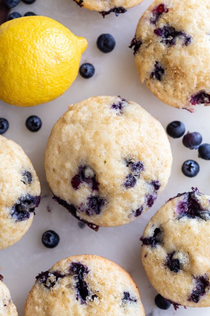 Lemon blueberry muffin near fresh blueberries and a lemon.