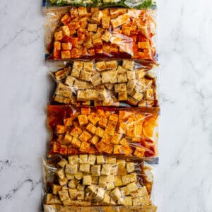 6 gallon baggies filled with tofu cubes and varies flavors and colors of tofu marinade