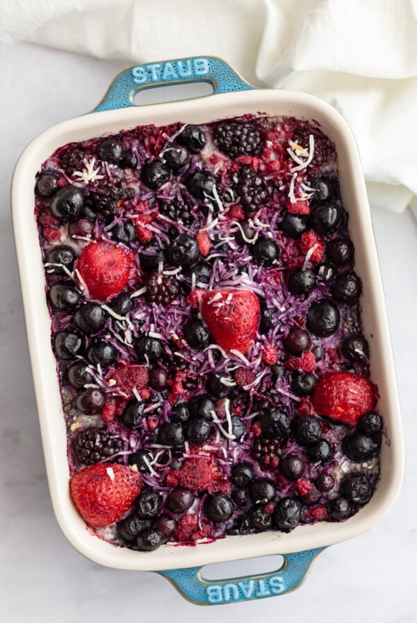 mixed berry topped baked oatmeal in a green staub casserole dish