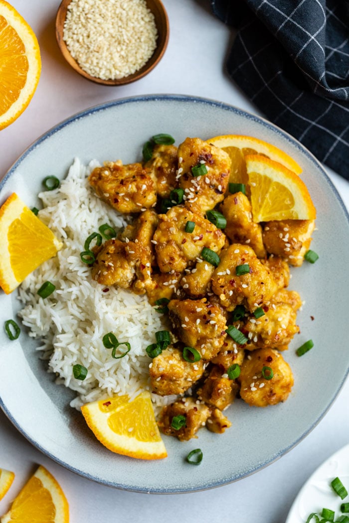 orange tofu served over rice with orange wedges